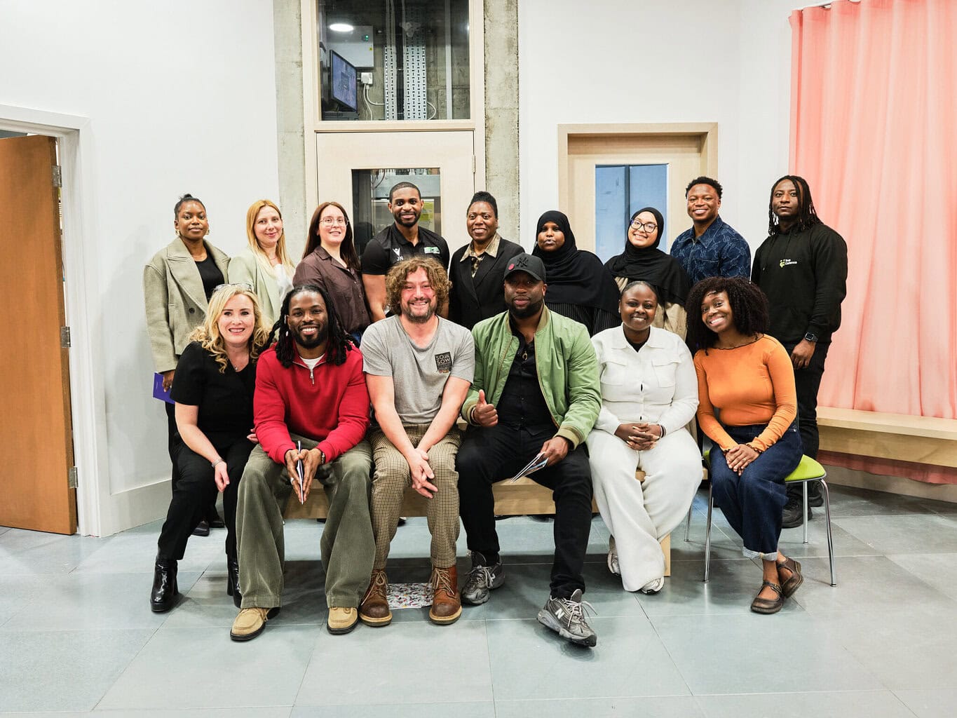 A landscape photo of 15 entrepreneurs smiling, with 6 sat on a bench and 9 stood behind. They are our GROW 2026 finalists.